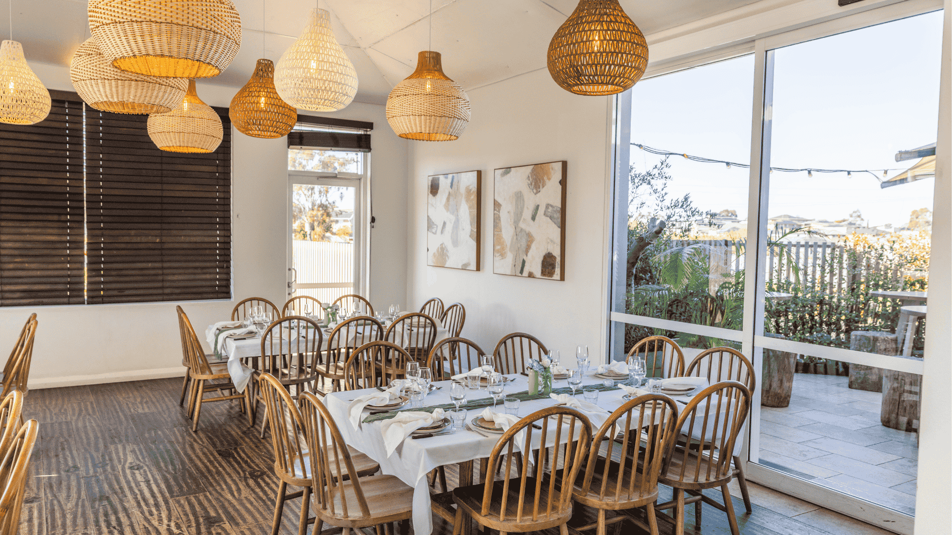 room with set dining tables, wooden chairs, woven pendant lights, and views of the outdoor terrace