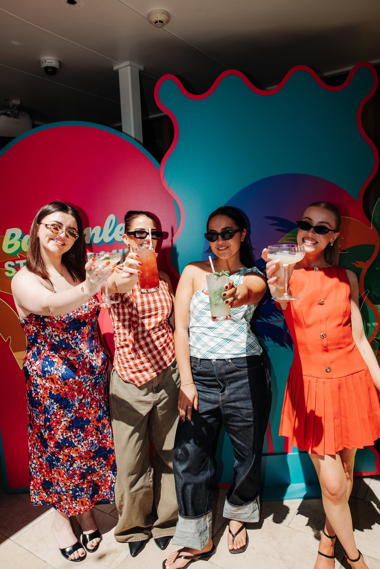 a group of friends holding cocktails up to the camera